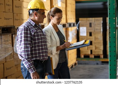 Female manager and warehouse worker checking list and inventory on the shelf in storehouse.