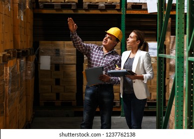 Female manager and warehouse worker checking list and inventory on the shelf in storehouse.