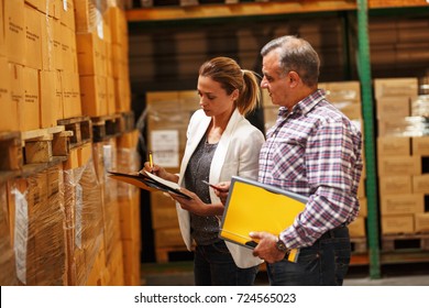 Female manager and warehouse worker checking list and inventory on the shelf in storehouse.