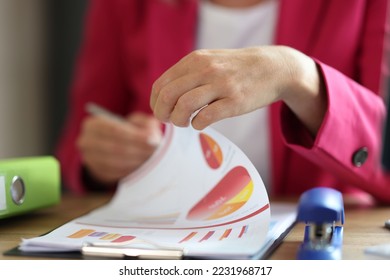 Female manager working with financial document on clipboard in office. Business woman correcting marketing data at her desk.