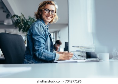 Female Manager Working At Her Desk. Smiling Businesswoman Sitting In Office.