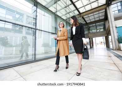 female managers meet in a business context outside near a modern building made of mirrors: They laugh and joke amiably .. - Shutterstock ID 1917940841