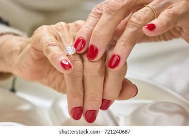 Female manicured hands with diamond. Senior woman hands with red nails and golden ring with diamond. Womans hands with precious jewels.