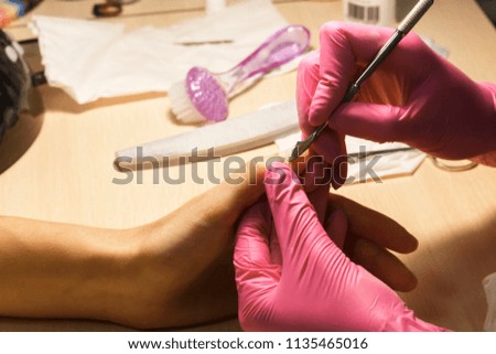 Female manicurist cleaning cuticle. girl does manicure, manicure of beautiful female hands, problem skin on the fingers, working process
