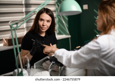 female manicurist masterfully covering the nail with transparent gel polish. Coating nails with gel polish in the beauty salon. Professional care for hands. - Shutterstock ID 2246755879