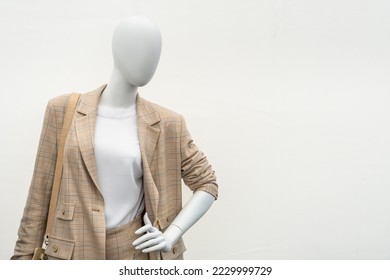 A female mannequin in a suit on a shop window. Sale of modern fashionable clothes. Bright youth clothing wholesale and retail.