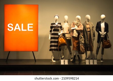 Female mannequins near red stand ''Sale''. Standing dummies in spring autumn collection. Shop window clearance - Shutterstock ID 2109598214