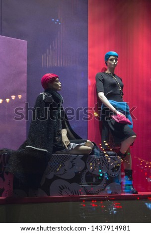 Female mannequins in a shop window and reflected lights of the city at night
