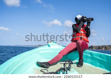 Female marine biologist taking photos while working on a boat in the middle of the sea in a sunny day