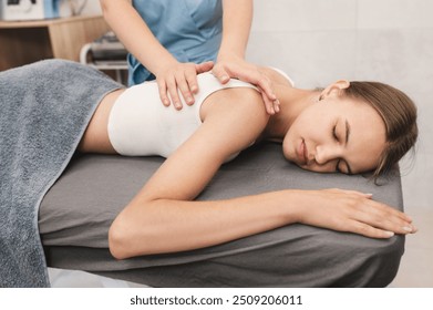 Female masseur massaging back and shoulder blades of young woman lying on massage table. Concept of massage spa treatments.
 - Powered by Shutterstock