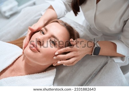 Female masseuse makes a professional facial massage to a patient ストックフォト © 