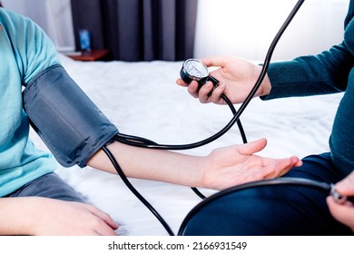Female measuring blood pressure of a child using the pressure sleeve and her stethoscope. at home. close up