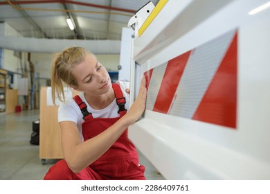 female mechanic applying reflective sticker to a car