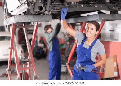 Female mechanic checking the rear suspension shock absorber of a car - Powered by Shutterstock