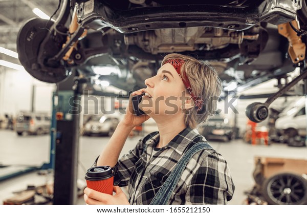 Female\
mechanic in a garage taking a coffee\
break