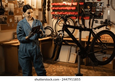 Female mechanic in a repair bike in bicycle store holding digital tablet. Copy space - Powered by Shutterstock