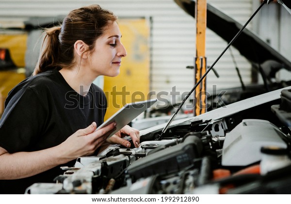 Female\
mechanic running a diagnostic on a car\
engine