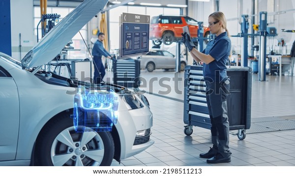 Female Mechanic Uses a Tablet Computer with an\
Augmented Reality Diagnostics Software. Specialist Inspecting Car\'s\
V6 Engine in Order to Find Broken Components. Hi-tech Modern Car\
Service.