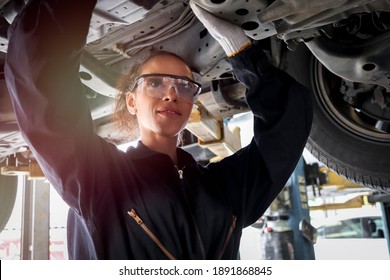 Female mechanic work in garage, car service technician woman checking and repairing customer’s car at automobile service center, inspecting car underbody and suspension system, vehicle repair service - Powered by Shutterstock