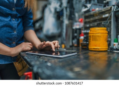 Female mechanic at work. Using a tablet while fixing a bicycle. Female bicycle repair technician using digital tablet in bicycle shop. Mechanic woman checking something on a tablet-pc and checklist.
 - Powered by Shutterstock