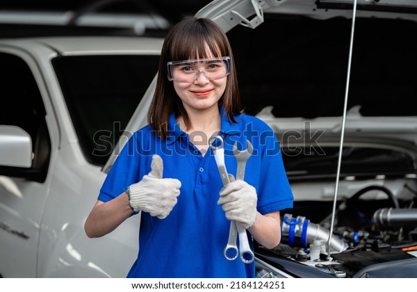 Female mechanic working in a car mechanic\
garage. A female mechanic repairs a customer\'s car at a car service\
center. Car inspection. Auto repair shop. Service concept. Auto\
repair service concept.