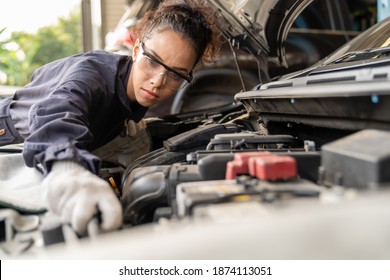 Female mechanic working at the garage. Professional female car mechanic examining, repair and maintenance under hood of car at auto car repair service. Car service and Maintenance concept - Powered by Shutterstock