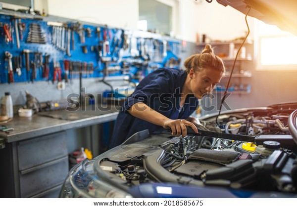 Female mechanic working on car tyre service.
Portrait Of Female Auto Mechanic Working Underneath Car. Portrait
of smiling young female mechanic inspecting a CV joing on a car in
auto repair shop