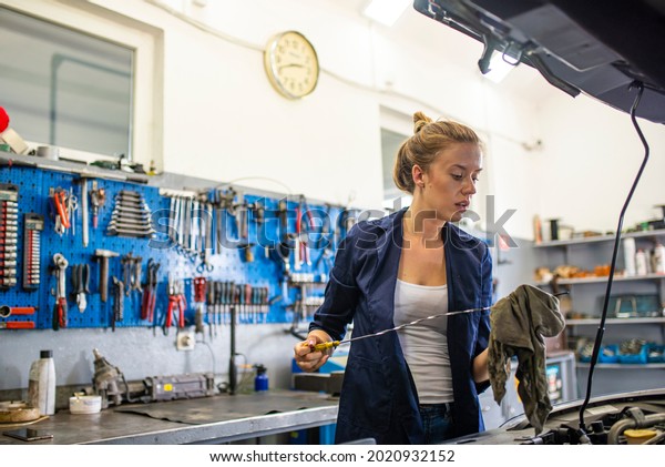 A female mechanic\
working under the hood of a car. An attractive woman mechanic\
working on a car in a repair shop. Mechanic working under the hood\
at the repair garage. 