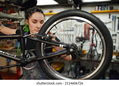 Female mechanic with wrench repairing bike in workshop - Powered by Shutterstock