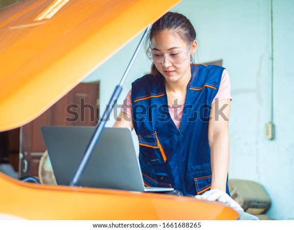 Female mechanical in the garage. Female mechanic\
fixing a car. Concept of service or repair motor car. Female\
checking in the garage.