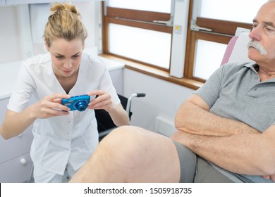 Female Medical Doctor Taking A Picture Of Injured Leg