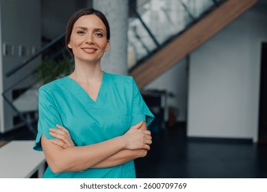 Profesional médica femenina irradia confianza, de pie con los brazos cruzados y una cálida sonrisa en un entorno hospitalario moderno, mostrando profesionalismo y experiencia en la atención médica
