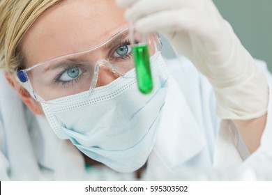 Female Medical Or Research Scientist Or Doctor Using Looking At A Test Tube Of Green Solution In A Lab Or Laboratory 