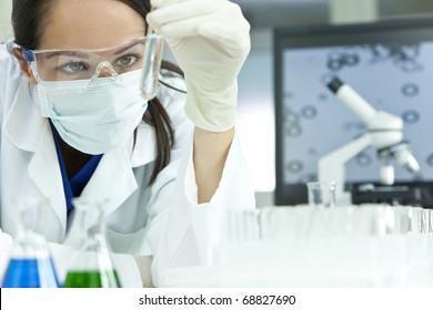 A female medical or scientific researcher or woman doctor looking at a test tube of clear solution in a laboratory with her microscope beside her. - Powered by Shutterstock