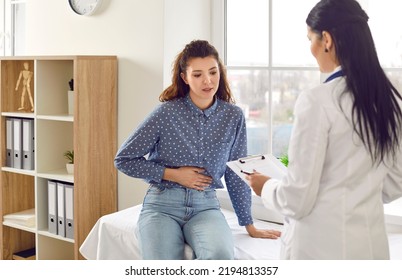 Female Medical Specialist Consults Young Female Patient Who Complains Of Abdominal Pain. Woman Experiences Abdominal Discomfort Due To Menstrual Pain, Pancreatitis, Gastritis Or Diarrhea.