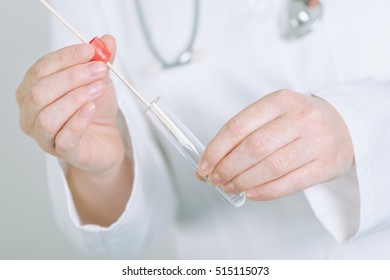 Female Medical Specialist Holding Buccal Cotton Swab And Test Tube, Ready To Collect DNA From The Cells On The Inside Of A Person's Cheek.