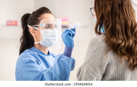 Female medical staff worker wearing protective equipment takes sample from nose of a patient to antigen test for coronavirus.