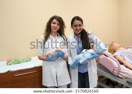 Female medical students with baby dolls in the hospital. Medicine practice of childbirth. Health care concept