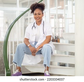 Female Medical University Student, Doctor In Lab Coat Sitting In Hospital. Portrait Of Woman Health Care Nurse With Stethoscope Works In Clinic. Healthcare And Medicine Professional Occupation Concept