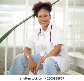 Female Medical University Student, Doctor In Lab Coat Sitting In Hospital. Portrait Of Woman Health Care Nurse With Stethoscope Works In Clinic. Healthcare And Medicine Professional Occupation Concept