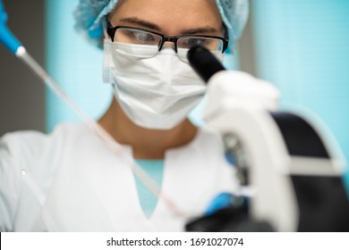 Female Medical Worker Conducting Laboratory Research With Microscope, Test Tubes, Medicines, Chemicals And Analyzes Examining Viruses And Other Human Diseases