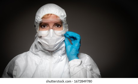 Female Medical Worker Wearing Protective Face Mask and Gear Against Dark Background. - Powered by Shutterstock