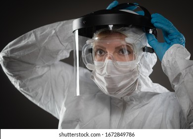 Weibliche Ärztin, die Schutzmaske und Zahnräder auf dunklem Hintergrund trägt.