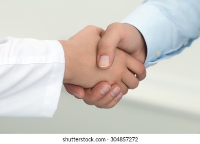 Female Medicine Doctor Shaking Hands With Male Patient. Partnership, Trust And Medical Ethics Concept. Handshake With Satisfied Client. Healthcare And Medical Concept