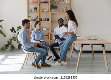 Female Mentor And Intern Sitting, Standing In Circle On Corporate Training Meeting, Talking, Laughing. Business Project Leader Talking To Employees, Brainstorming, Having Fun