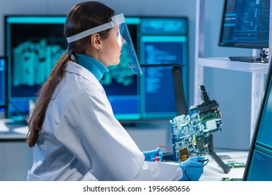 Female microelectronics engineer works in a scientific laboratory on computing systems and microprocessors. Professional electronic factory worker is testing the motherboard and coding the firmware.