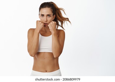 Female middle aged fighter standing in defensive boxing pose, boxer practice and workout punched, clench fists near face and jumpin, doing sport, white background - Powered by Shutterstock