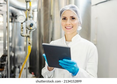 A Female Milk Plant Supervisor Scrolling On Tablet And Smiling At The Camera.