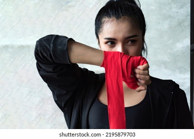 A female mixed martial artist is wrapped in a red boxing bandage. Strong hands ready for close combat, exercise and sparring. Women's self-defense. - Powered by Shutterstock