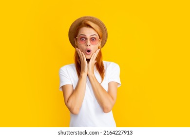 Female model with amazed expression, surprised face. Young redhead woman in straw hat, surprised expression, isolated on yellow background. Summer lifestyle studio portrait.